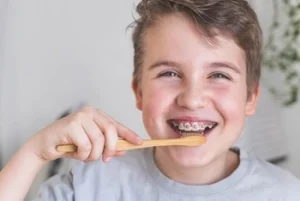 little boy with braces brushing teeth